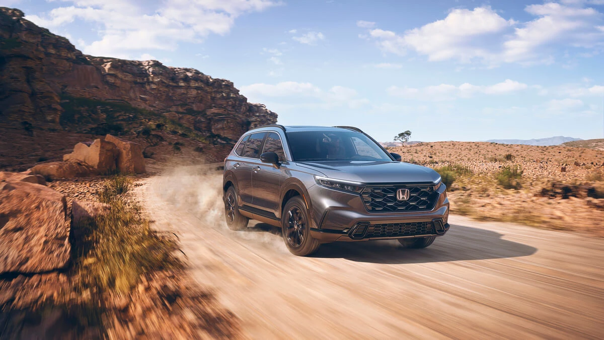 Grey 2024 Honda CR-V Sport driving in a desert landscape.